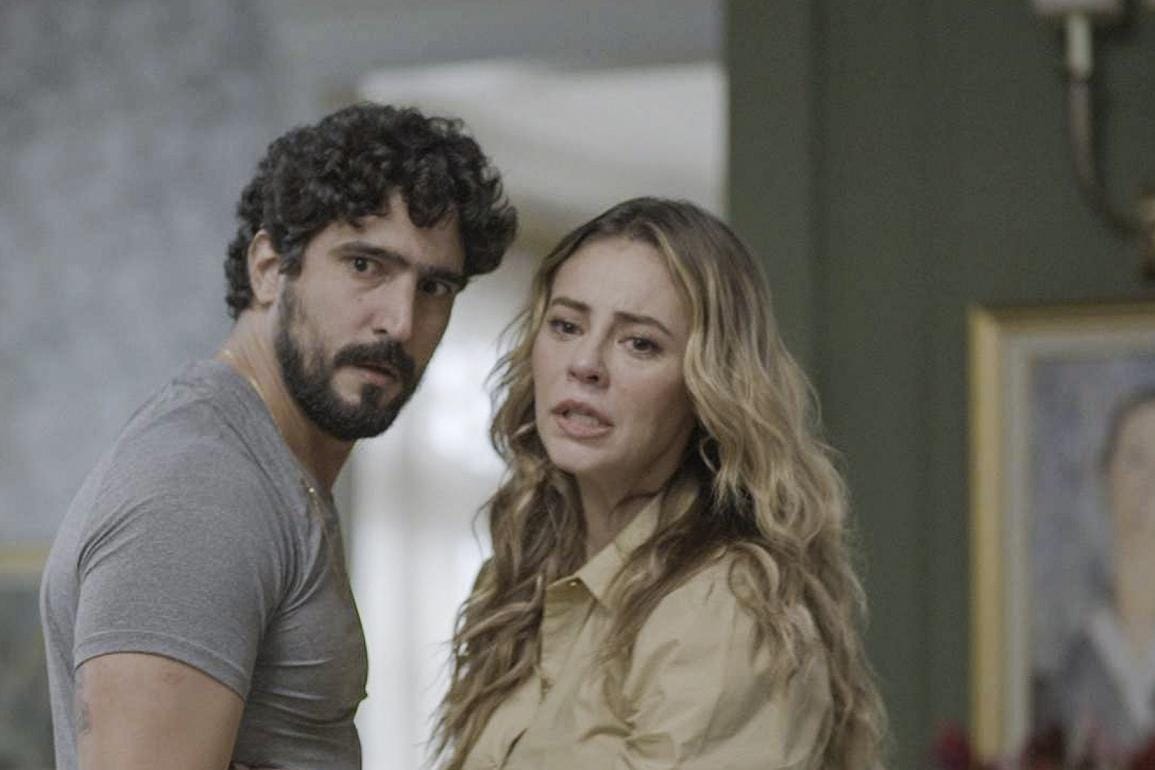 Um casal em uma conversa tensa e emocional em um ambiente moderno, representando a dinâmica de Ivan e Heleninha em 'Vale Tudo 2025'.